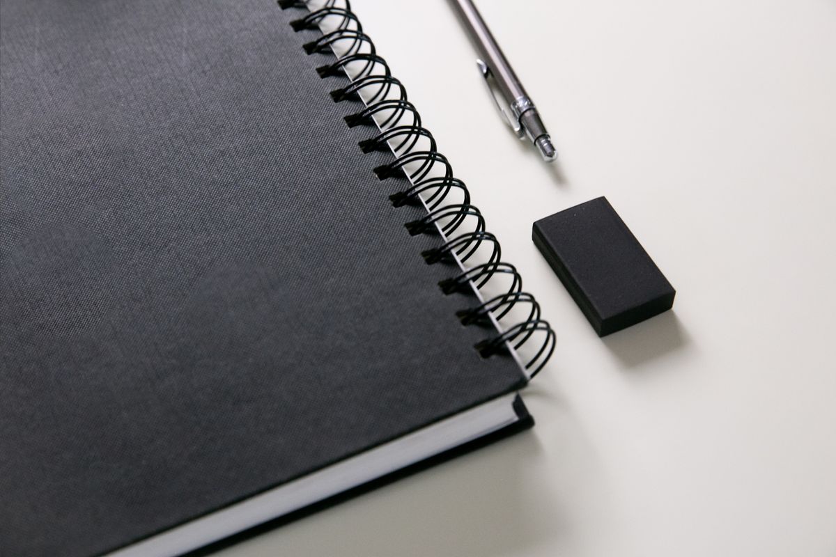 Black spiral notebook with a pen and eraser arranged beside it