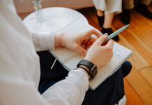 Close-up of a person writing notes in a notebook during a conversation
