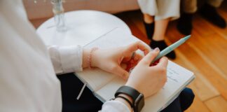 Close-up of a person writing notes in a notebook during a conversation