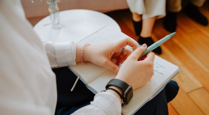 Close-up of a person writing notes in a notebook during a conversation
