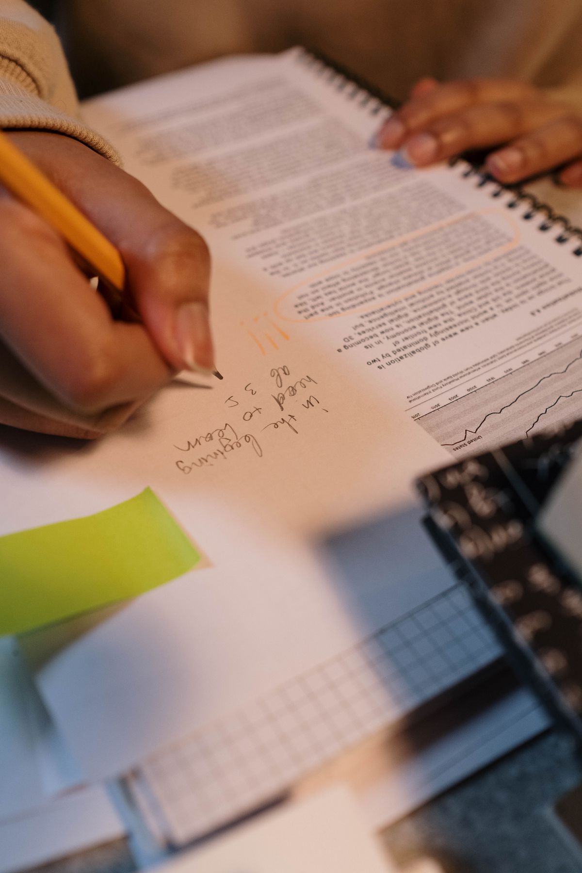 Close-up of a hand writing notes in a spiral notebook