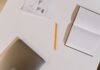 Notebook and pencil beside a laptop on a white desk