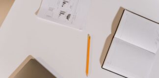 Notebook and pencil beside a laptop on a white desk