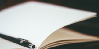 Close-up of a pen resting on an open notebook