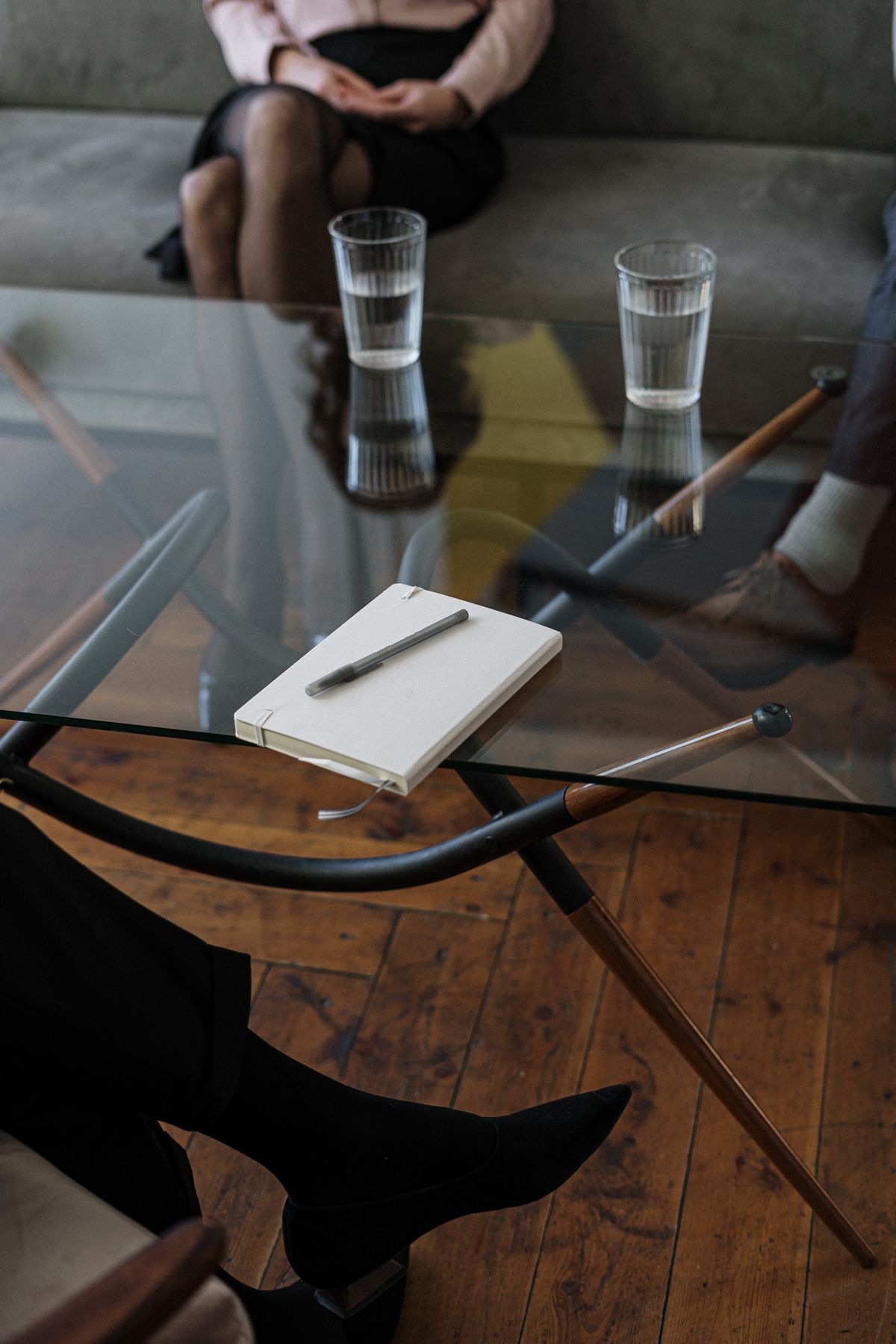 Two glasses of water and a notepad on a glass table during a counseling appointment