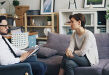 Man and woman seated on a sofa talking in an office