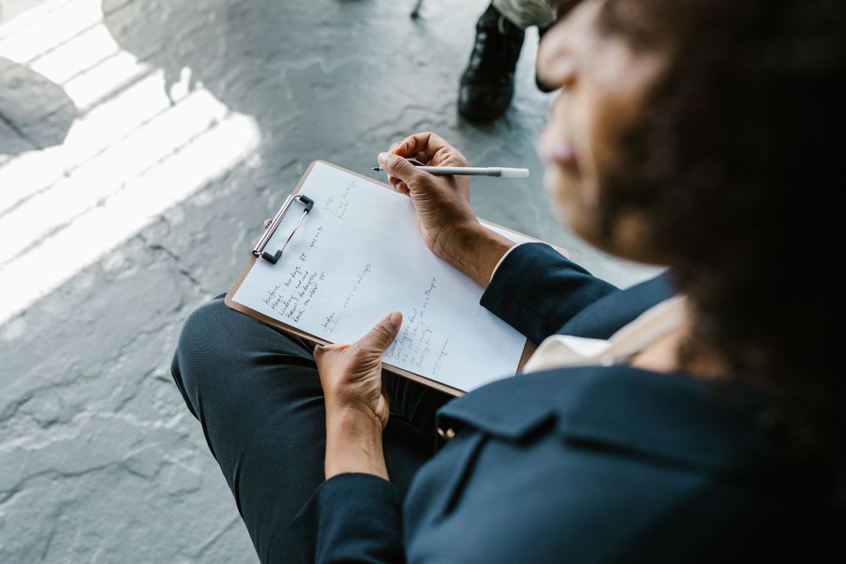 Close-up of a therapist writing notes on a clipboard