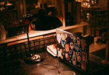 Laptop, lamp, and books on a warmly lit desk