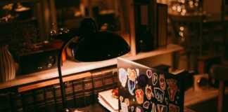Laptop, lamp, and books on a warmly lit desk