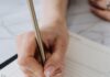 Hand writing in an open planner with a pencil