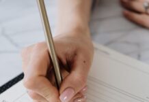 Hand writing in an open planner with a pencil
