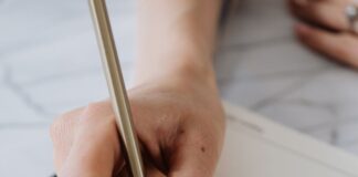 Hand writing in an open planner with a pencil
