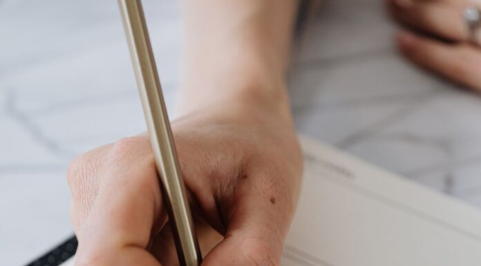 Hand writing in an open planner with a pencil