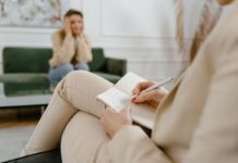 Therapist writing notes during a consultation with a seated client