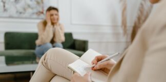 Therapist writing notes during a consultation with a seated client