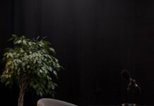 Empty gray chair beside a black table and a houseplant