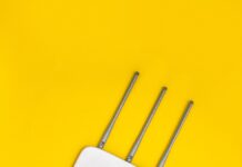 White Wi-Fi router with antennas and cables on a yellow background