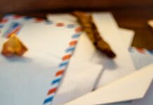 Envelopes arranged beside a compass and autumn leaves on a table