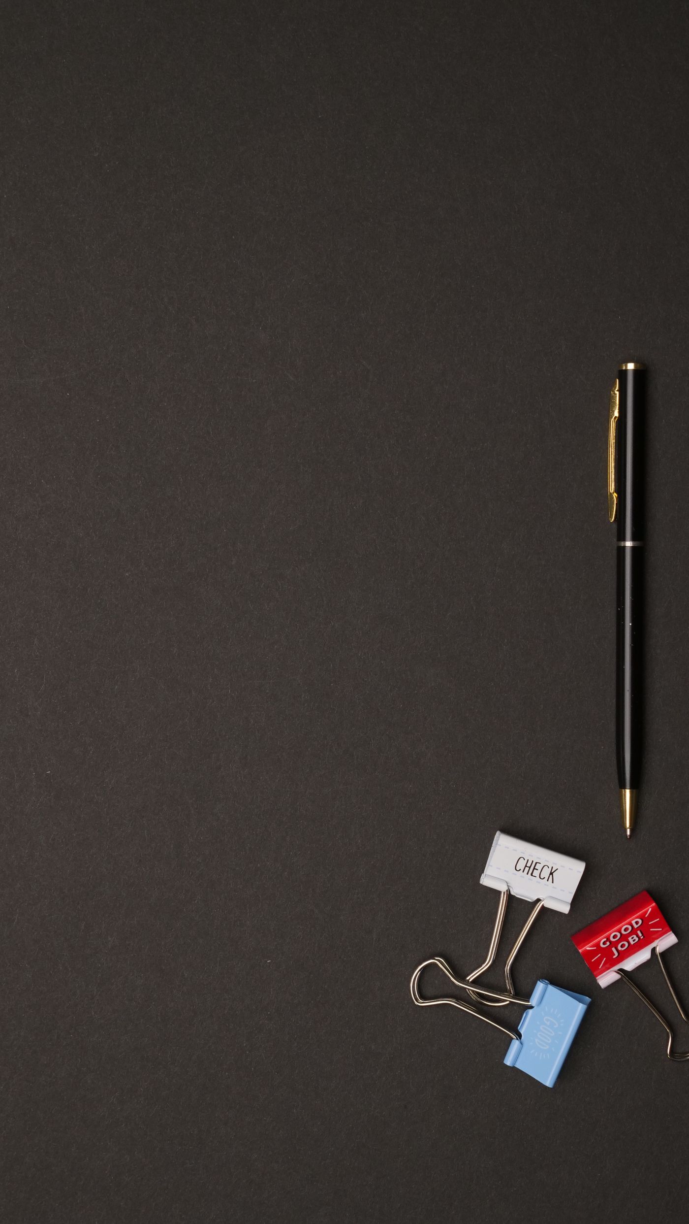 Black pen and binder clips arranged beside paperwork on a desk