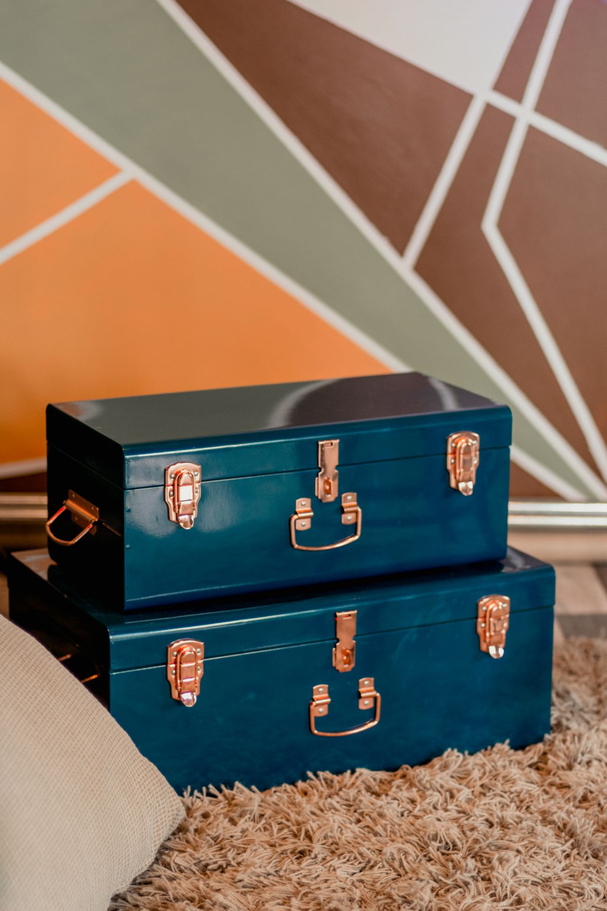 Two blue metal storage chests placed together on a rug indoors
