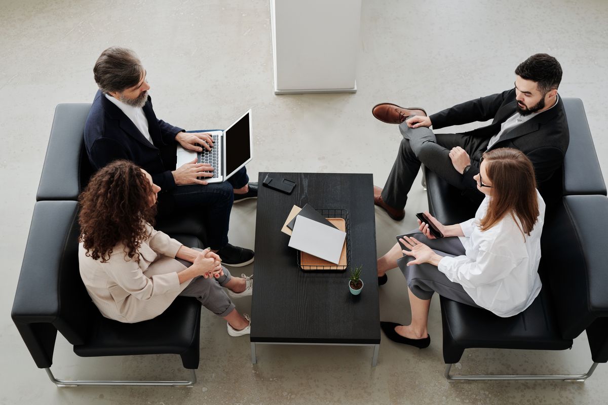 People seated on black leather sofas during a conversation in an office
