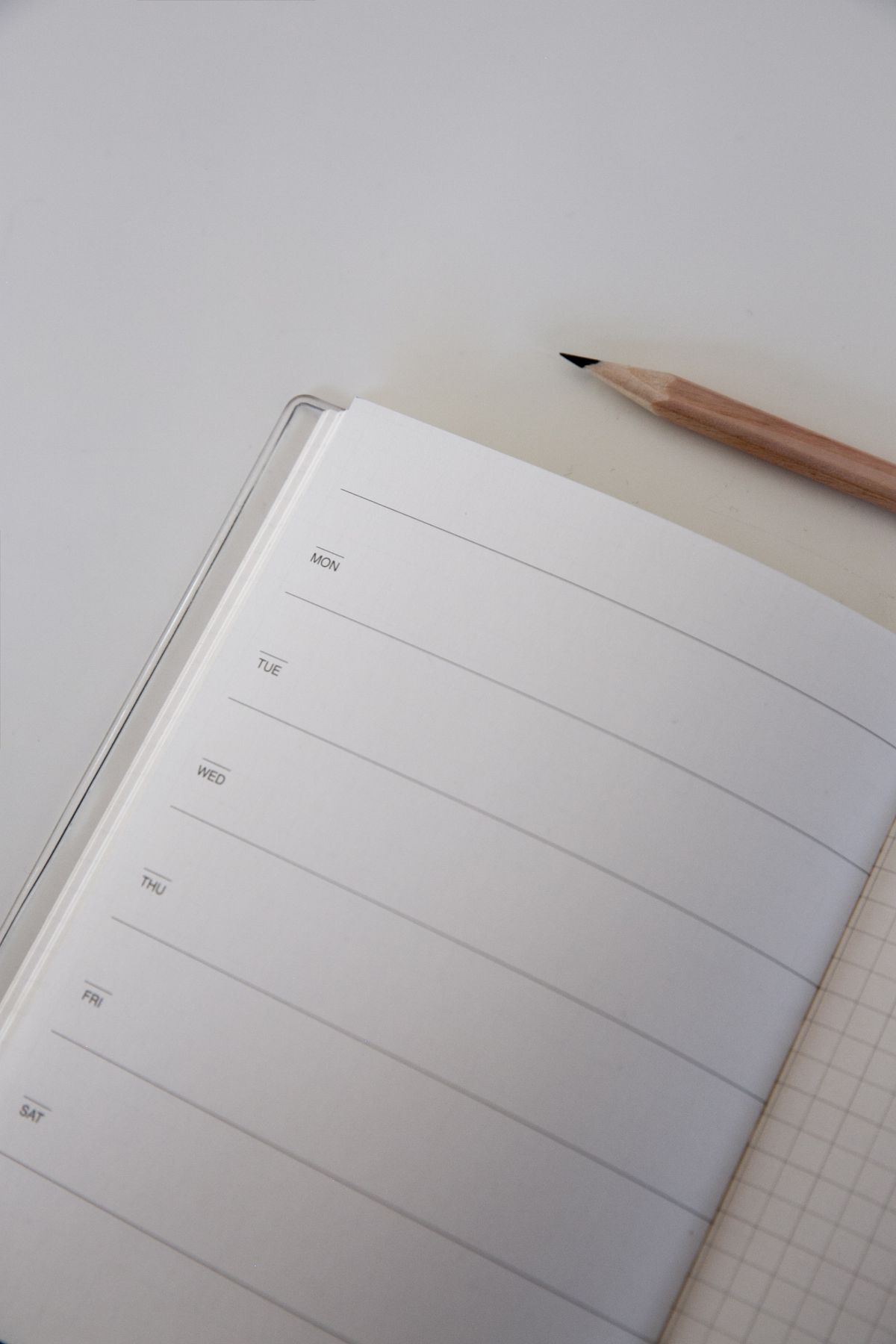 Open lined planner and brown pencil on a white surface