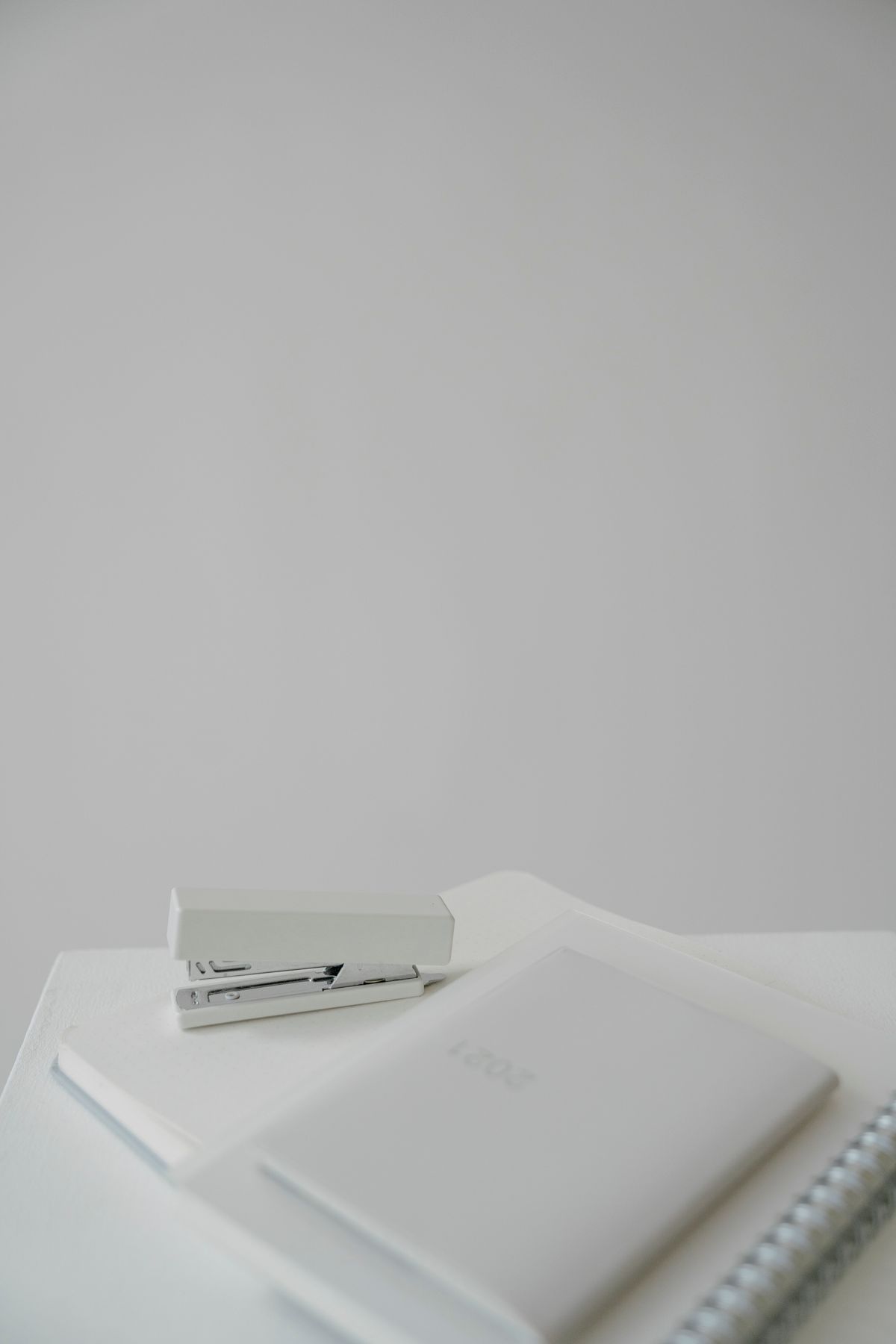 Notebook and white stapler arranged on a light office desk