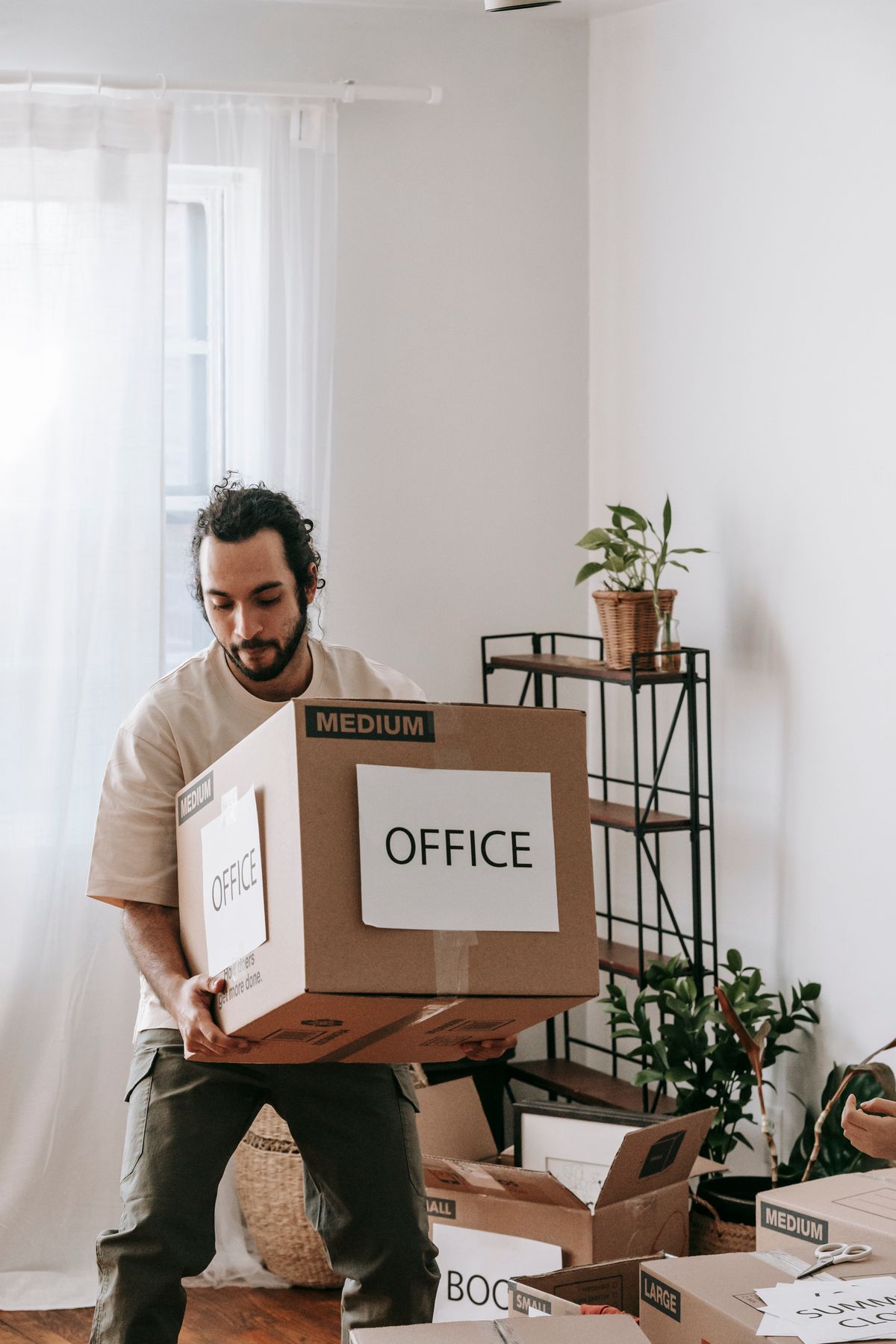 Man carrying a cardboard box marked Office during a move