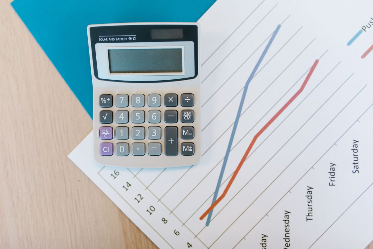 Calculator resting on financial charts and paperwork on a desk