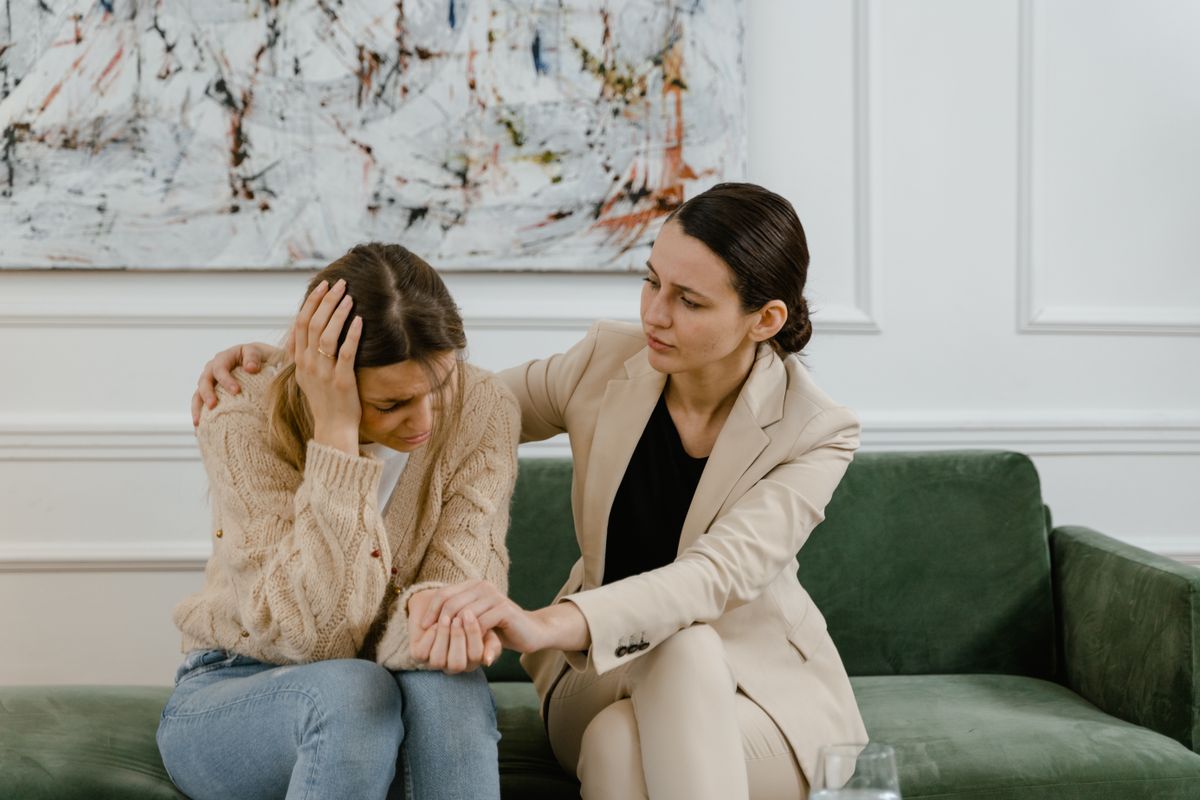 Two women sitting together in conversation on a green sofa