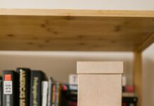 Cardboard boxes on a wooden bookshelf among books